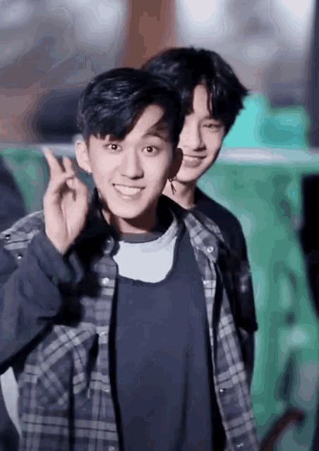 two young men are posing for a picture and one is making a heart sign