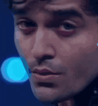a close up of a man 's face in front of a blue light