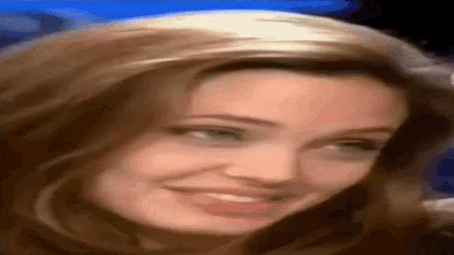 a close up of a woman 's face smiling and looking at the camera