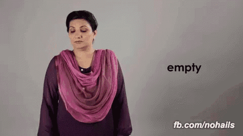 a woman wearing a purple dress and a pink scarf is standing in front of a wall with the word empty on it .
