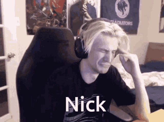 a man wearing headphones is sitting in a chair with the name nick written on his shirt .