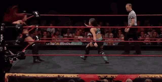 two women are wrestling in a wrestling ring with a referee watching .