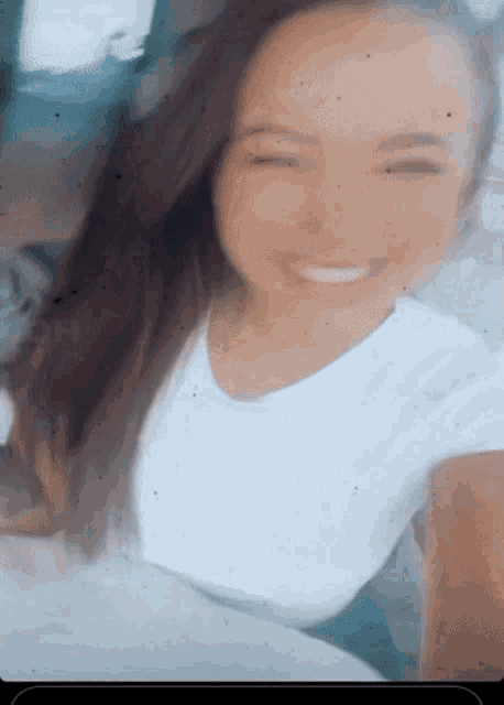 a woman in a white shirt is smiling and making a wink with her eyes closed