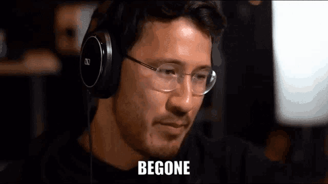 a man wearing headphones and glasses is looking at a computer screen .