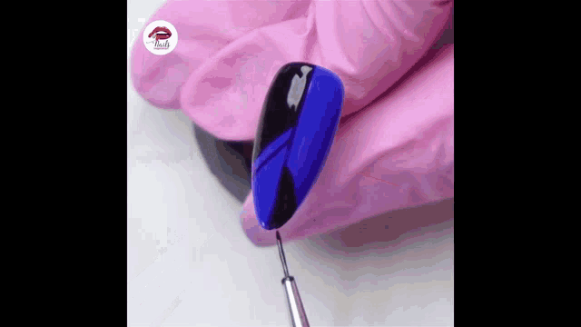 a person wearing pink gloves is applying blue nail polish to a nail