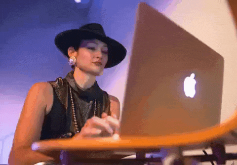 a woman in a hat is typing on a laptop