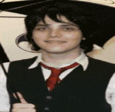 a young man wearing a vest and tie holds an umbrella