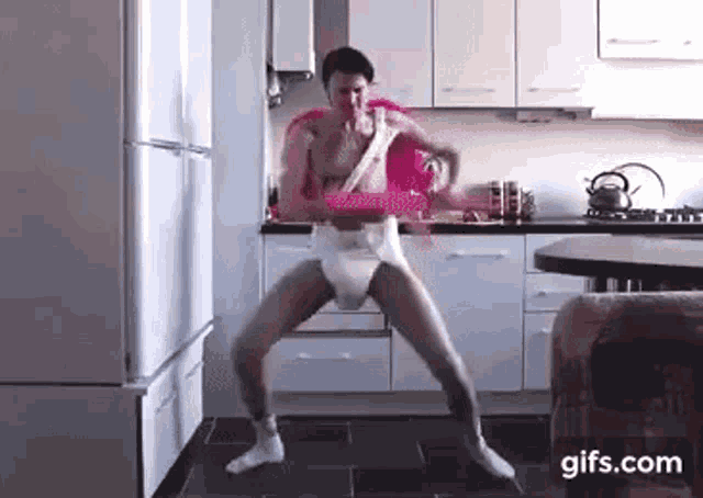 a man in a diaper is dancing in a kitchen while holding a pink hula hoop .