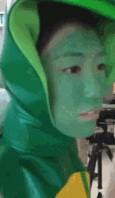 a person with green paint on their face is wearing a green hoodie