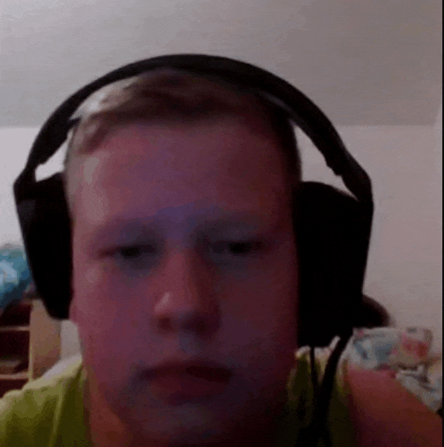 a young man wearing headphones is looking at the camera and making a funny face .