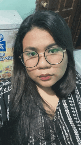 a woman wearing glasses is taking a selfie in front of a sign that says ice-cream