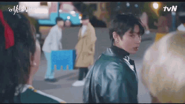 a man in a leather jacket is standing next to a woman in a trench coat .