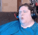 a fat man wearing headphones is sitting on a couch .