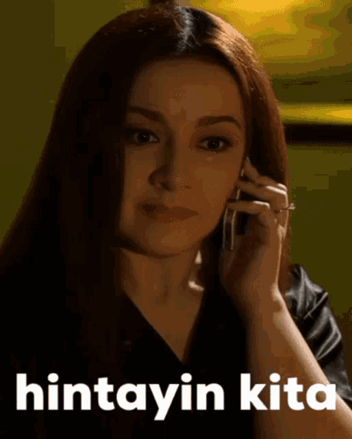 a woman is talking on a cell phone with the word hintayin kita written below her