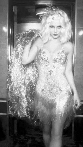 a black and white photo of a woman in a dress with a crown on her head