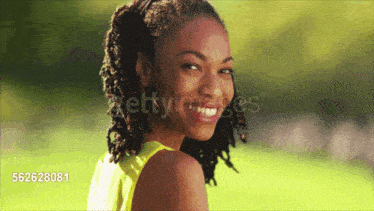a woman with dreadlocks is smiling in a park