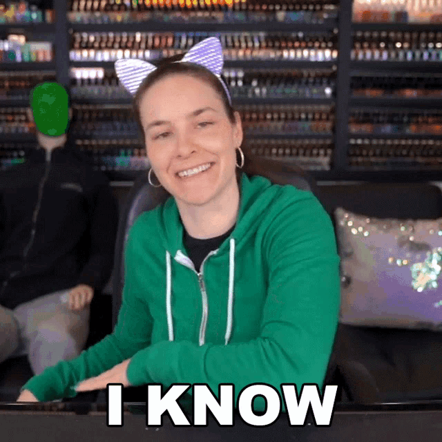 a woman in a green hoodie is smiling and says i know