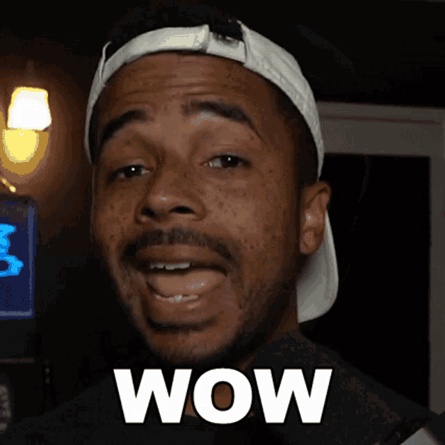 a man wearing a white hat is making a surprised face and the word wow is on his face