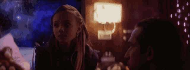 a man and a little girl are sitting at a table in a dark room .