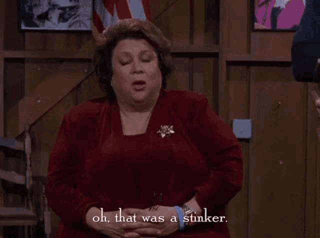 a woman in a red dress is holding her stomach and says oh that was a stinker .