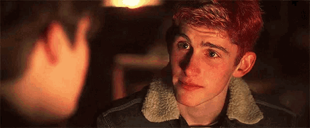 a young man with red hair is looking at another young man with green eyes .