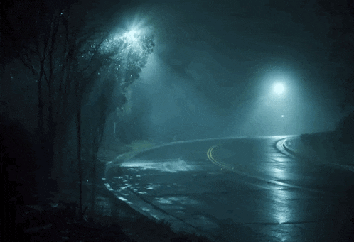 a dark road with a street light on the right side