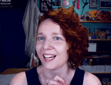 a woman with red hair is smiling in front of a screen that says raid