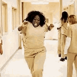 a woman is running down a hallway in a jail cell .