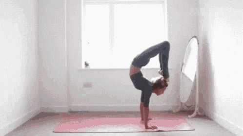 a woman is doing a handstand in front of a mirror .
