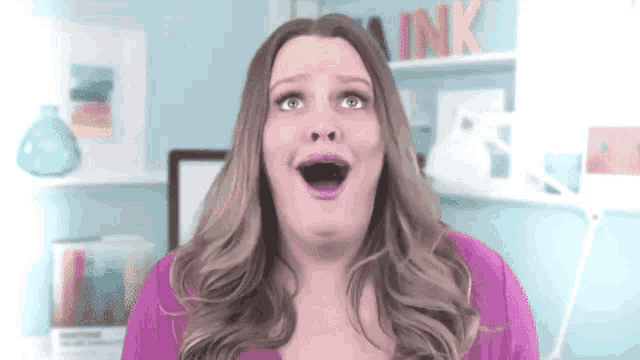 a woman in a pink shirt is making a surprised face in front of a sign that says ink