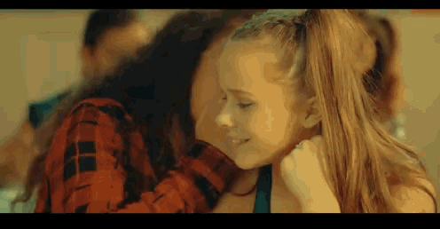 a woman is holding a little girl in her arms and the little girl is smiling .