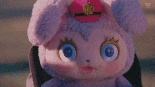 a stuffed animal with blue eyes and a pink hat is being held by a person .