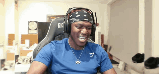 a man wearing a bandana and headphones is smiling while sitting in a chair .