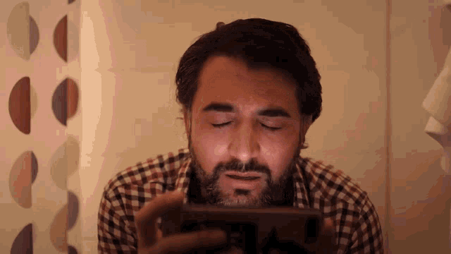 a man in a plaid shirt is looking at a cell phone