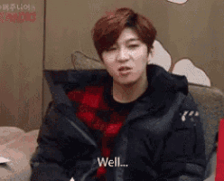 a young man in a black jacket is sitting on a couch and making a face .