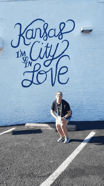 a woman kneeling in front of a wall that says kansas city i 'm so in love