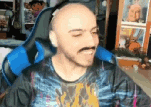 a bald man with a beard and mustache is sitting in a blue chair .