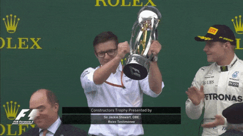 a man is holding a trophy that says constructors trophy presented by sir jackie stewart