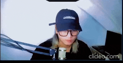 a person wearing a hat and glasses is sitting in front of a microphone .