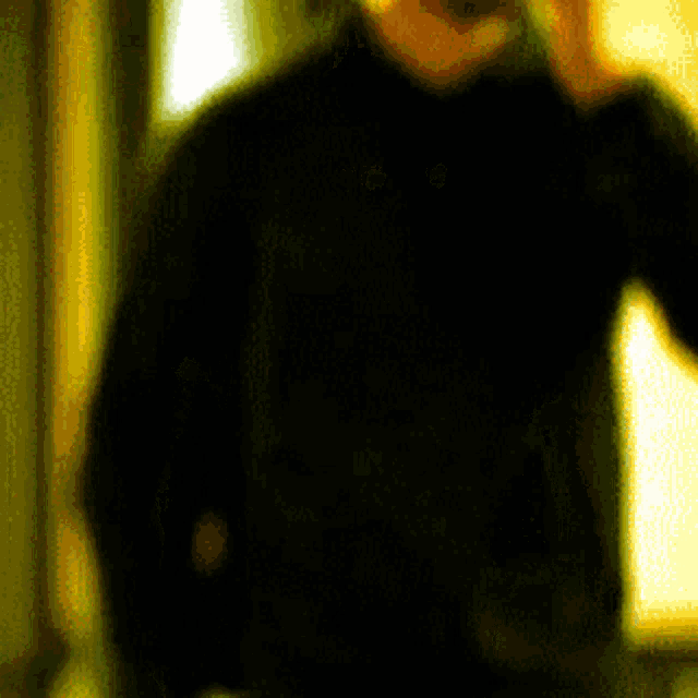 a blurry picture of a man in a black shirt talking on a cell phone