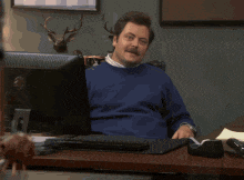 a man giving a thumbs up in front of a computer monitor