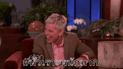a man in a suit is sitting in a chair and laughing in a room .