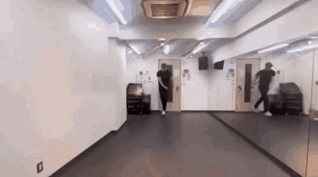 a man is dancing in a dance studio with a large mirror .