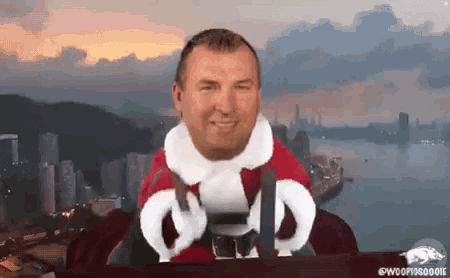 a man in a santa suit is sitting at a table in front of a river .