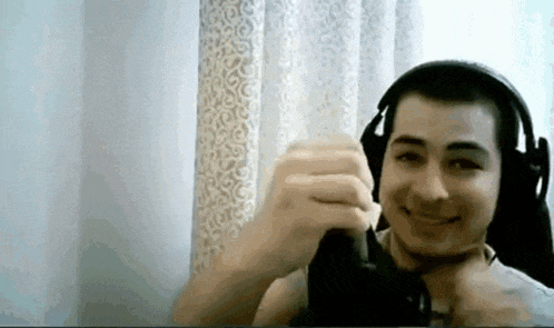 a man wearing headphones is making a funny face while sitting in front of a window .