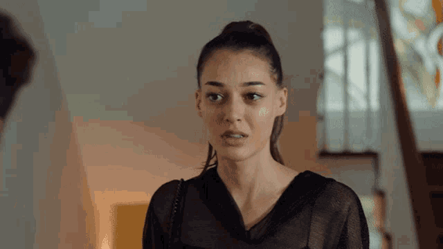 a woman in a black top looks at the camera with a serious look on her face