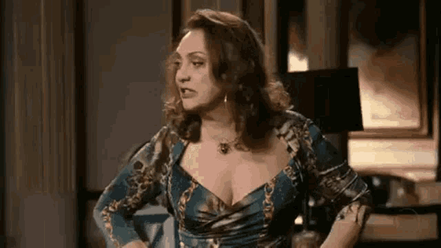 a woman in a blue dress with a plunging neckline is standing in a living room .