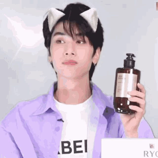 a young man wearing cat ears holds up a bottle of lotion