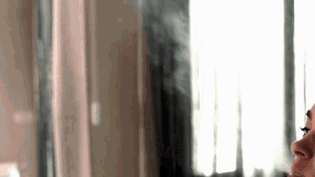 a close up of a person smoking a cigarette in front of a window