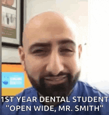 a bald man with a beard is smiling and talking to someone .
